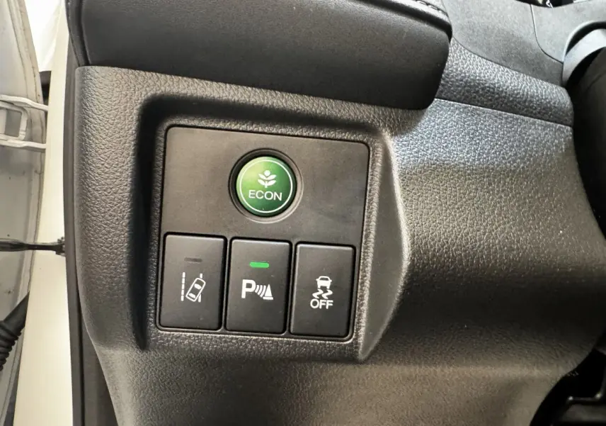 Gros plan sur les boutons de commande du tableau de bord du Honda HR-V blanc, avec bouton ECON vert et aides à la conduite.