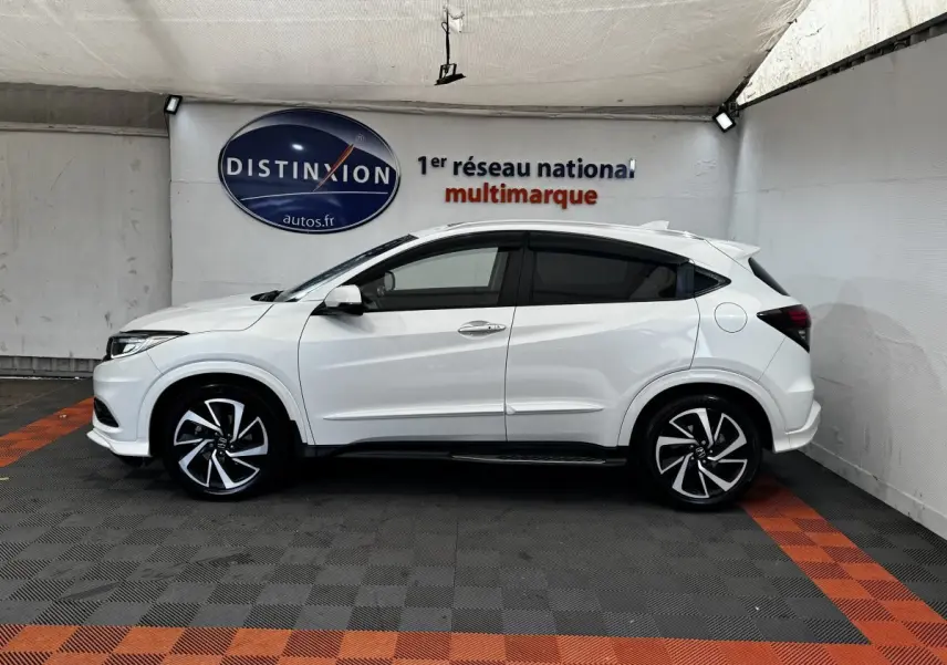Vue de profil côté gauche d'un Honda HR-V blanc 2019 avec jantes alliage noires et toit spoiler.