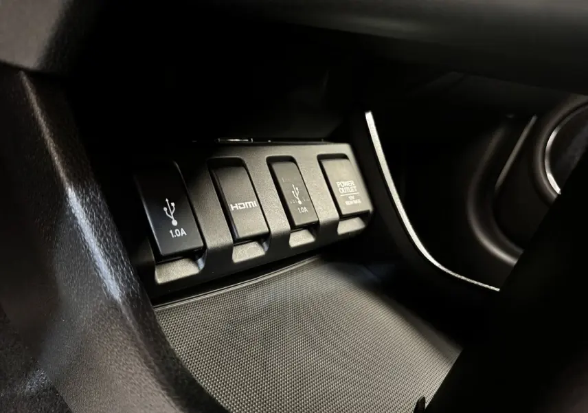 Gros plan sur les prises USB, HDMI et prise 12V noires dans l'habitacle du Honda HR-V 1.5 i-VTEC blanc.