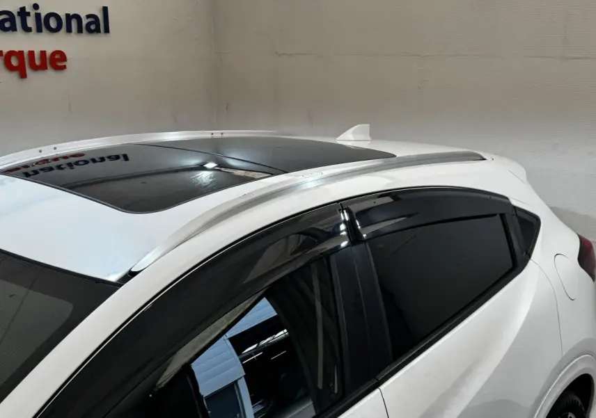 Vue rapprochée du toit ouvrant et des vitres teintées côté gauche d’un Honda HR-V blanc avec rails de toit chromés.