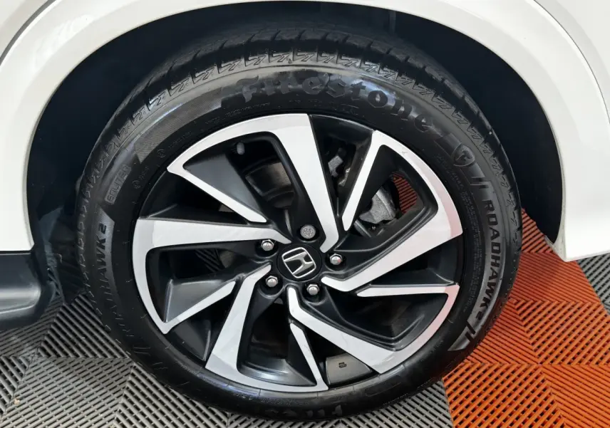 Gros plan sur la roue avant droite d’un Honda HR-V blanc, avec jante alliage noire et argentée distinctive.