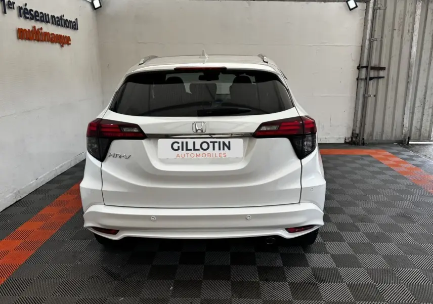 Vue arrière d'un Honda HR-V blanc 2019 avec spoiler de toit et feux arrière LED dans un garage.