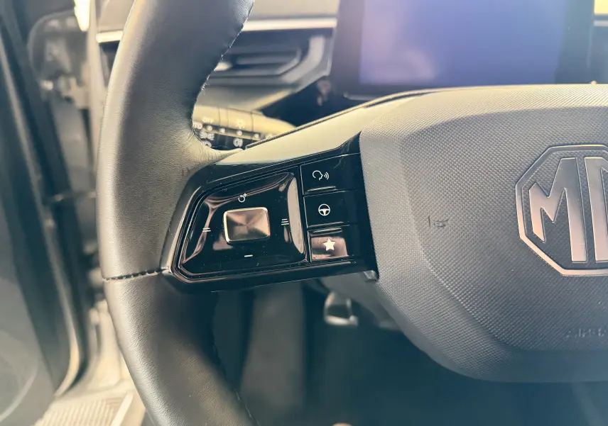 Gros plan sur la partie gauche du volant noir du MG3 2025, avec commandes intégrées et logo MG central.