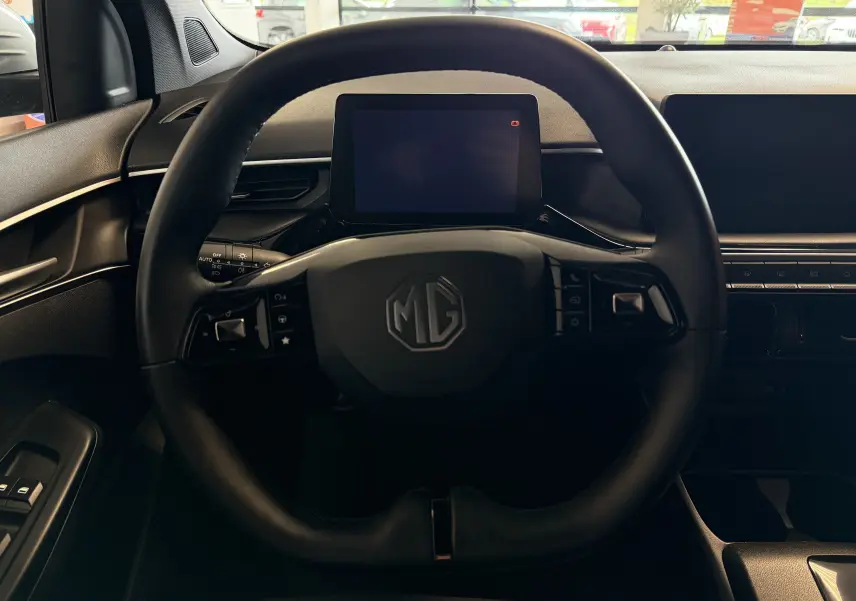 Vue intérieure centrée sur le volant MG d'une MG3 2025, avec écran tactile et tableau de bord noir.