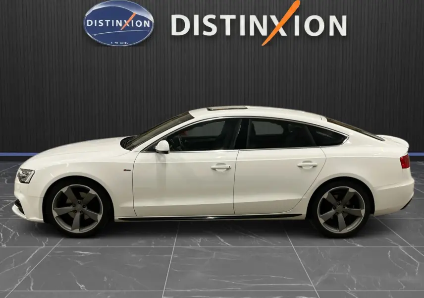 Audi A5 Sportback blanc vue de profil côté gauche, jantes 5 branches foncées et toit ouvrant panoramique.