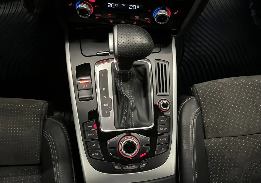 Vue plongeante sur la console centrale de l'Audi A5 Sportback blanche, mettant en valeur le levier de vitesse automatique et les commandes multimédia.