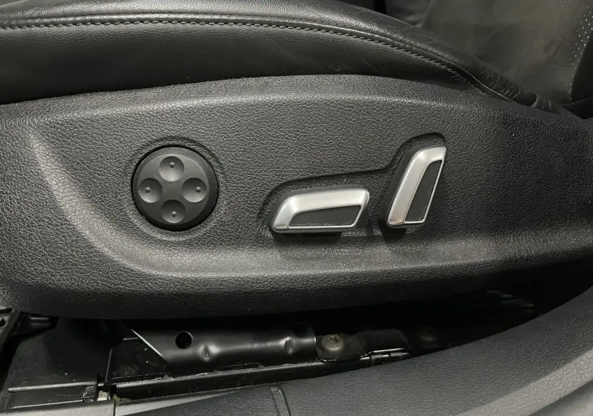 Gros plan sur les commandes électriques de réglage du siège en cuir noir de l'Audi A5 Sportback blanche.