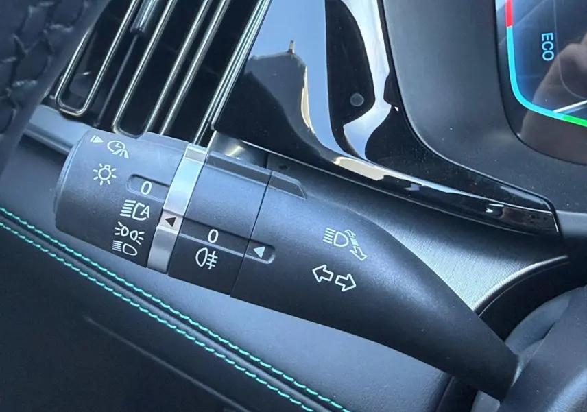 Gros plan sur la manette de clignotants et feux du tableau de bord intérieur du BYD SEAL U, finition noire avec surpiqûres vertes.