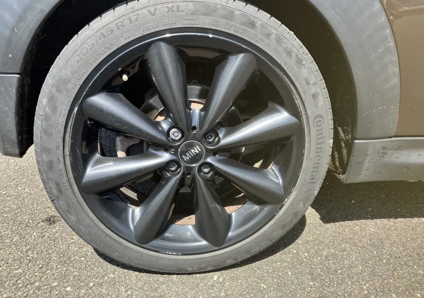 Gros plan sur la roue avant droite noire de la MINI Cooper S R56 marron de 2012 avec jante en alliage au design original.