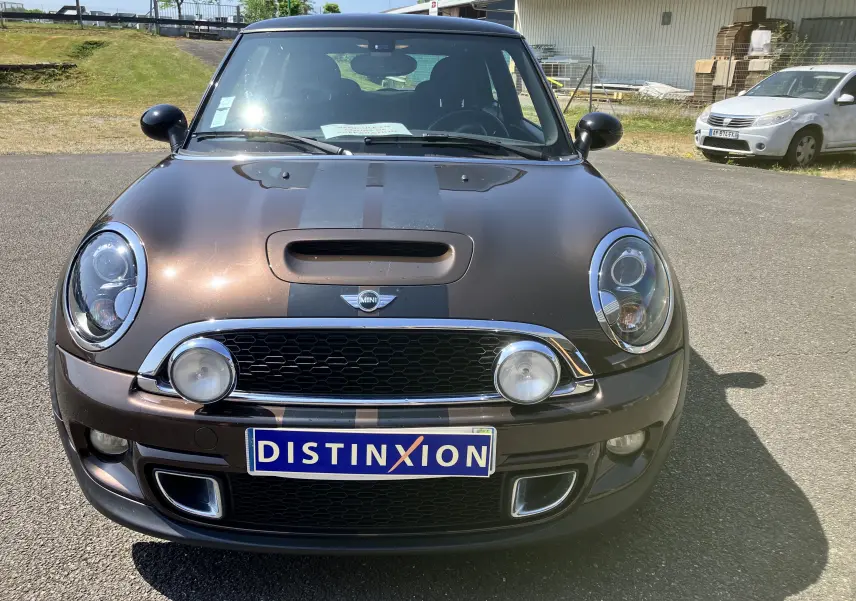 Vue frontale d'une MINI Cooper S R56 marron avec bandes noires sur le capot et phares ronds caractéristiques.
