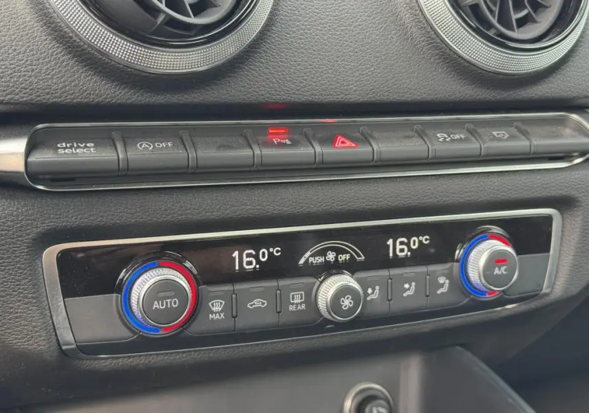 Gros plan sur la console centrale de l'Audi A3 Cabriolet gris, montrant les commandes de climatisation bi-zone et boutons de fonction.