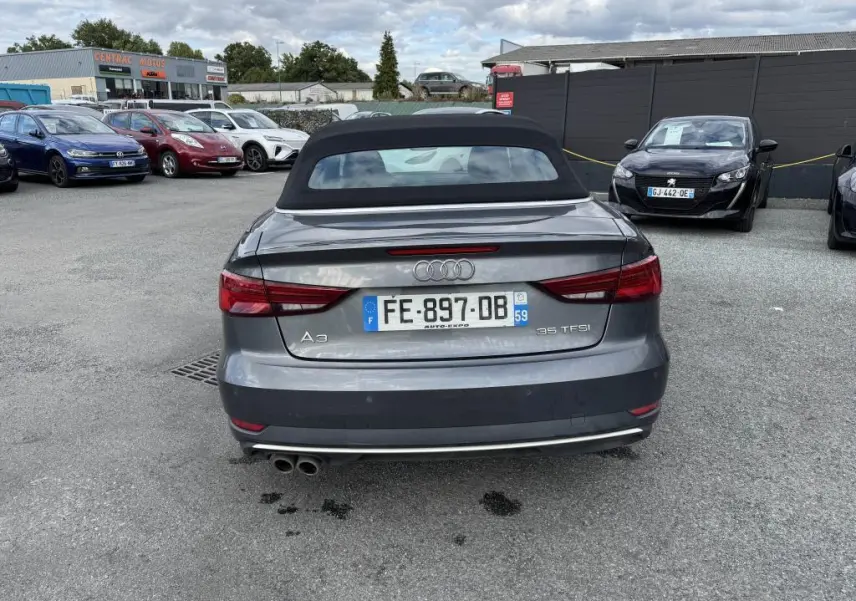 Vue arrière d'une Audi A3 Cabriolet gris métallisé avec capote noire et double sortie d'échappement chromée.