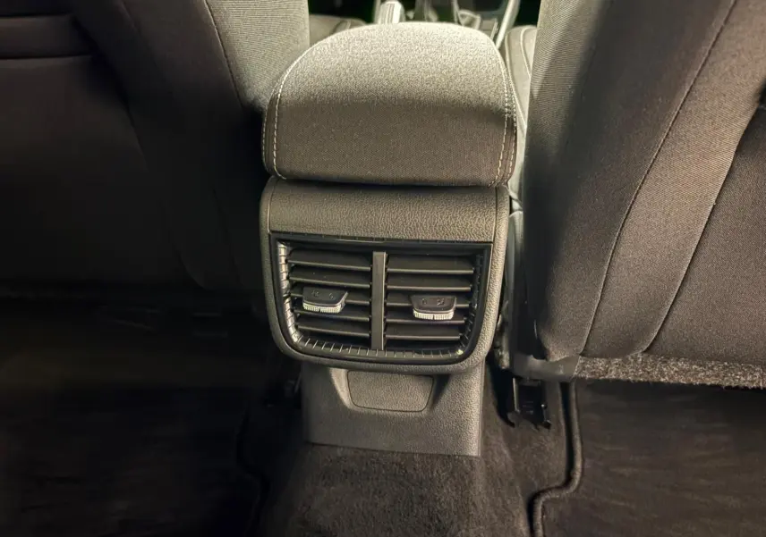 Vue intérieure arrière centrée sur la console de ventilation entre les sièges avant d’une Skoda Fabia gris graphite 2023.