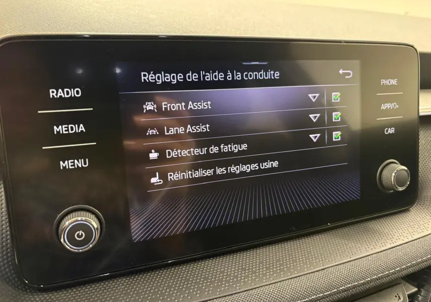 Écran tactile intérieur du Skoda Fabia 2023 affichant les réglages d’aide à la conduite, vue de face.