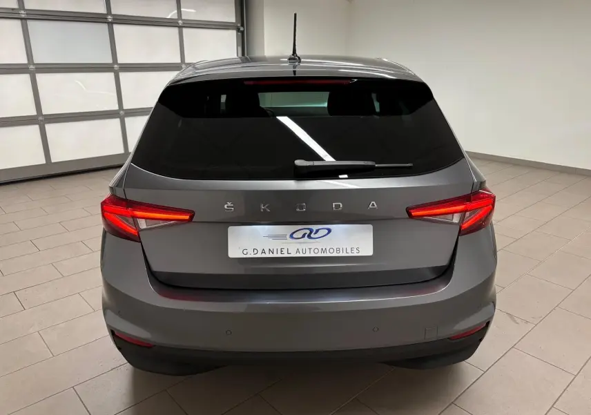 Vue arrière d'une Skoda Fabia 2023 gris graphite métallisé avec feux arrière allumés dans un garage.