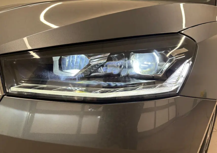 Gros plan sur le phare avant droit de la Skoda Fabia 2023 en peinture métallisée gris graphite, éclairage LED allumé.