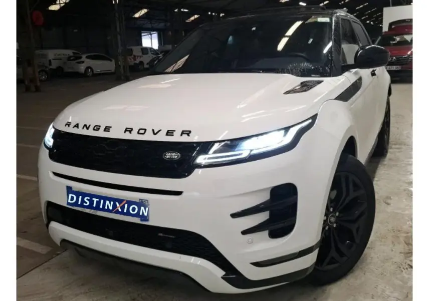 Vue 3/4 avant droite du Range Rover Evoque blanc avec toit noir et jantes noires dans un garage.