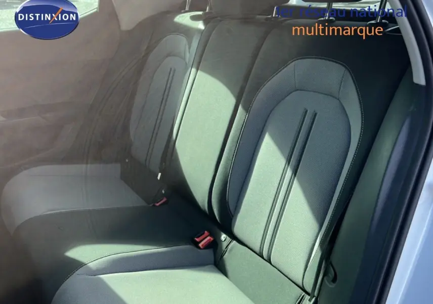 Vue intérieure des sièges arrière en tissu gris noir du SEAT LEON blanc neige, avec ceinture de sécurité visible côté droit.