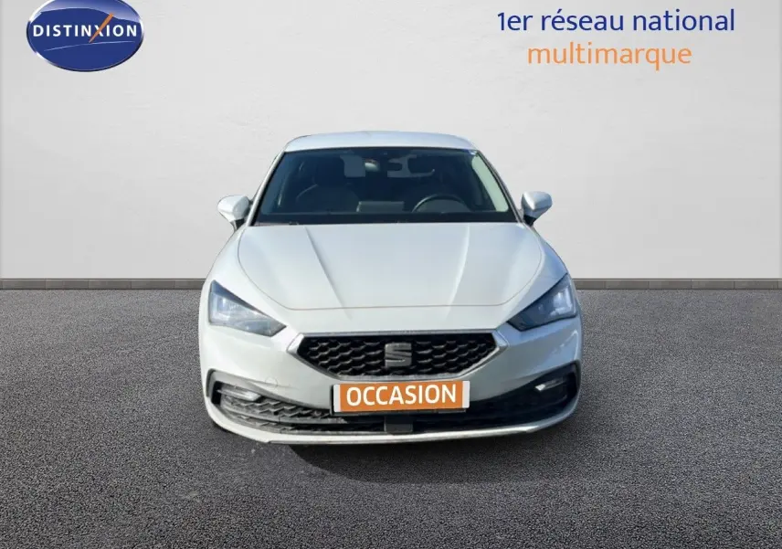 Vue frontale d'une SEAT Leon blanche neige 2025 avec calandre noire et phares LED allumés.