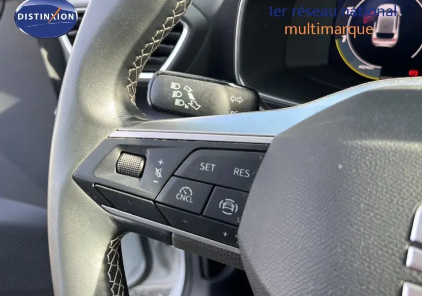 Gros plan sur le volant de la SEAT LEON blanc neige, mettant en valeur les commandes multifonctions côté gauche.