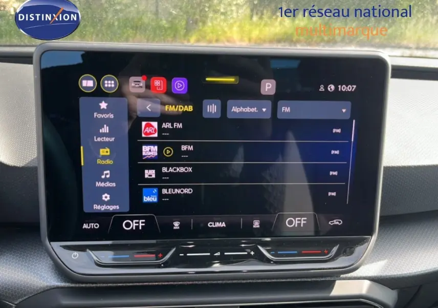 Écran tactile central affichant la radio FM dans l’habitacle d’une SEAT LEON blanc neige, vue de face.