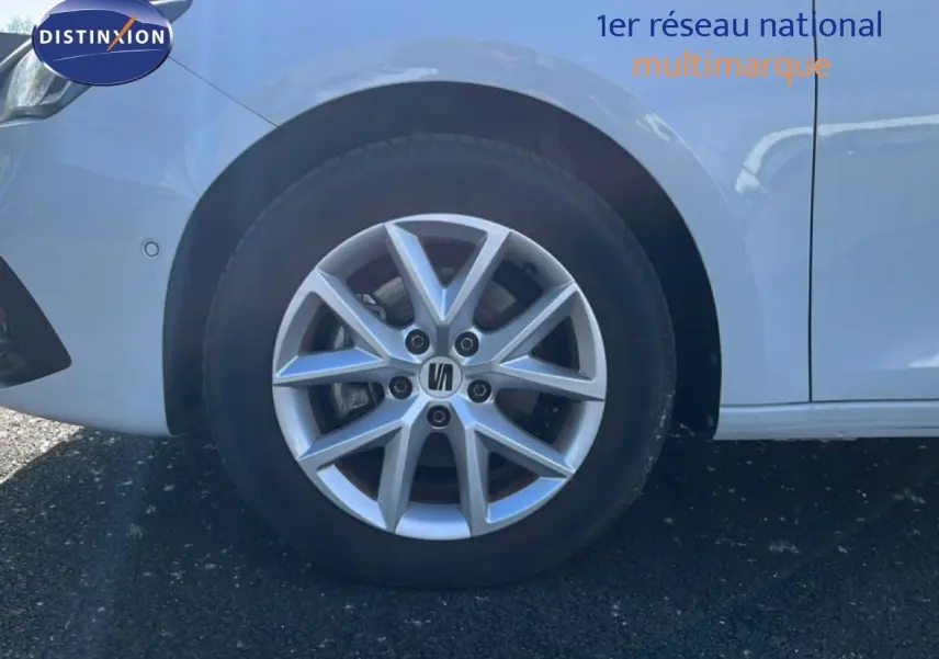 Gros plan sur la roue avant gauche d'une SEAT LEON blanc neige, mettant en valeur la jante alliage à 5 branches doubles.