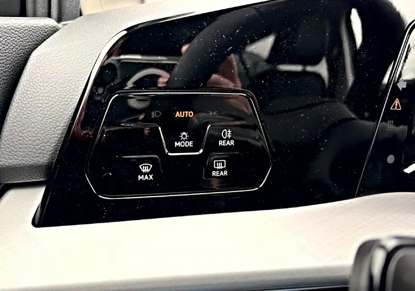 Gros plan sur les commandes de phares automatiques et dégivrage sur le tableau de bord noir de la Volkswagen Golf 2026.