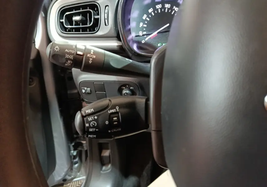 Gros plan sur la colonne de direction et le compteur, intérieur gris clair de la Citroën C3 BlueHDi 2024.