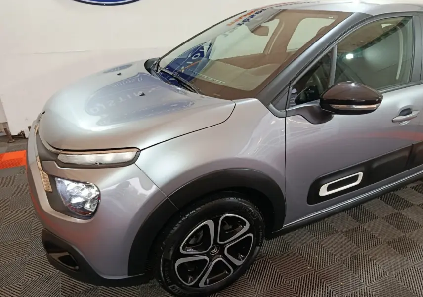 Vue 3/4 avant droit d'une Citroën C3 gris clair avec phares LED et jantes alliage noires distinctives.