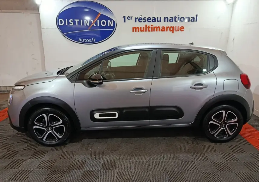 Profil côté gauche d'une Citroën C3 gris clair 2024 avec protections noires et jantes distinctives en concession.