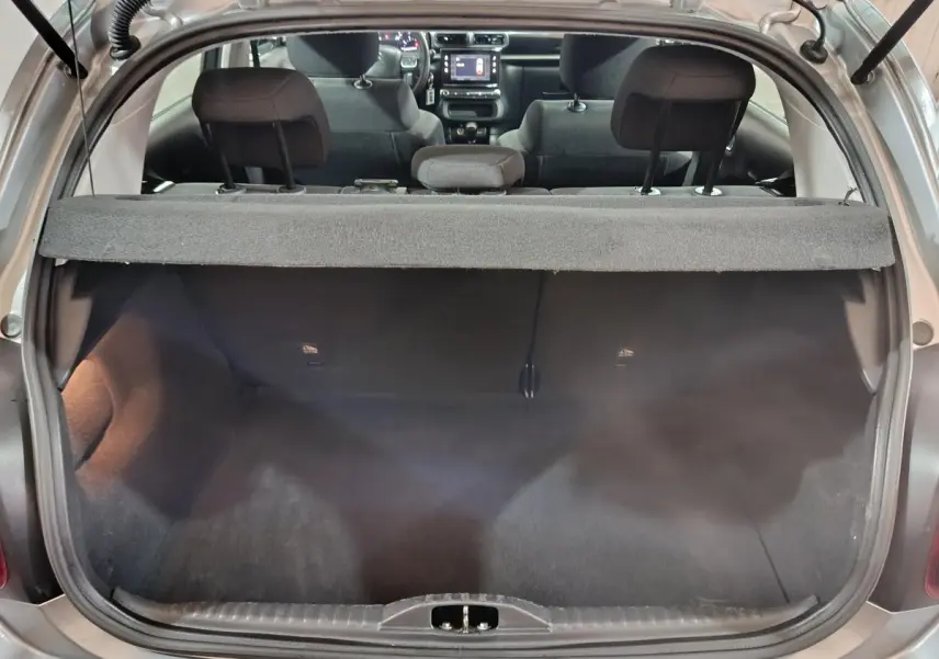 Vue arrière du coffre ouvert d'une Citroën C3 gris clair 2024, avec banquette arrière et tableau de bord visible.
