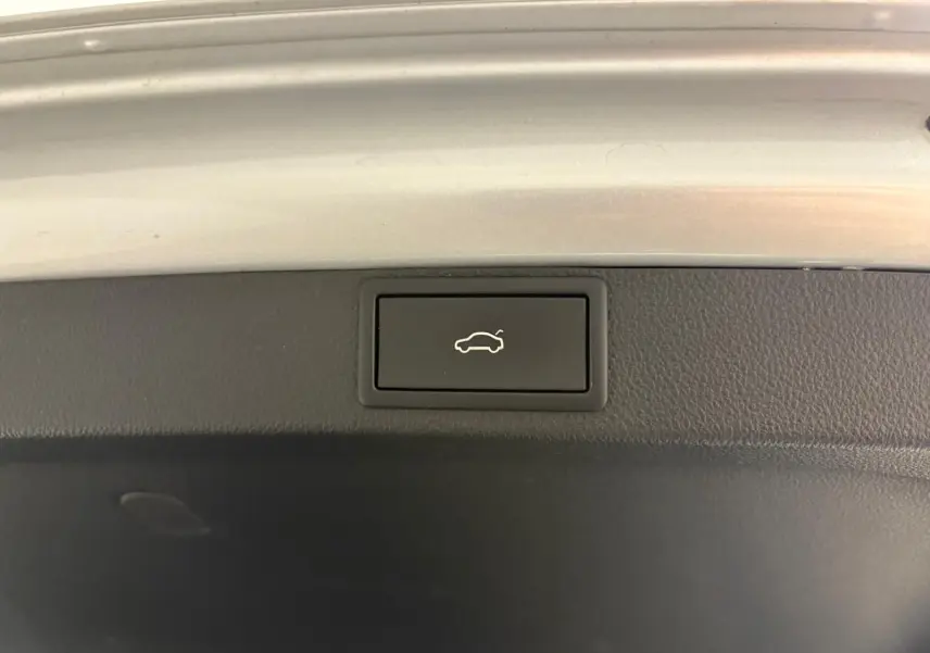 Bouton d'ouverture électrique du coffre sur la trappe intérieure d'une Skoda Octavia Combi gris argent 2023.