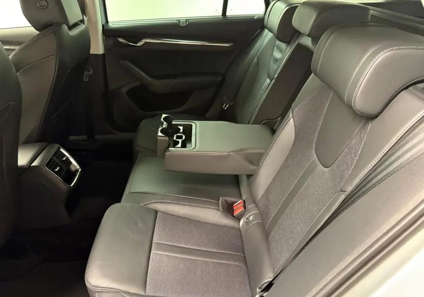 Vue intérieure côté droit des sièges arrière en cuir noir avec accoudoir central déployé de la Skoda Octavia Combi 2023 gris argent.