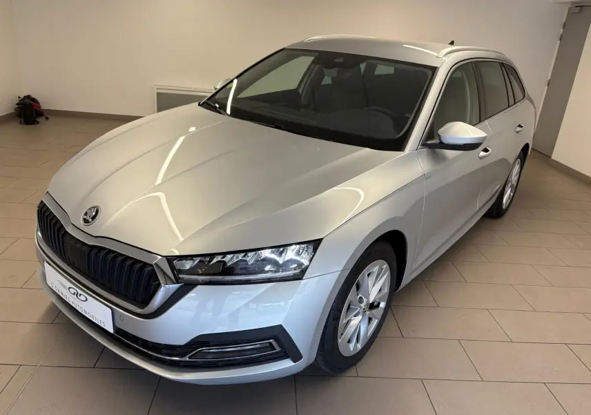 Vue 3/4 avant droite d'une Skoda Octavia Combi gris argent 2023 avec calandre noire et phares LED distinctifs.