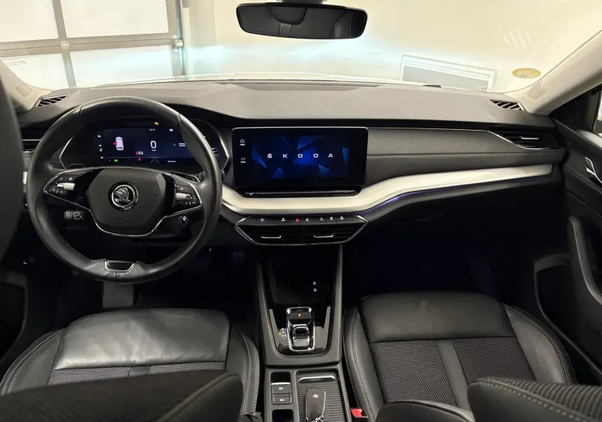 Intérieur noir de la Skoda Octavia Combi 2023, vue frontale sur le tableau de bord et volant avec écran digital.