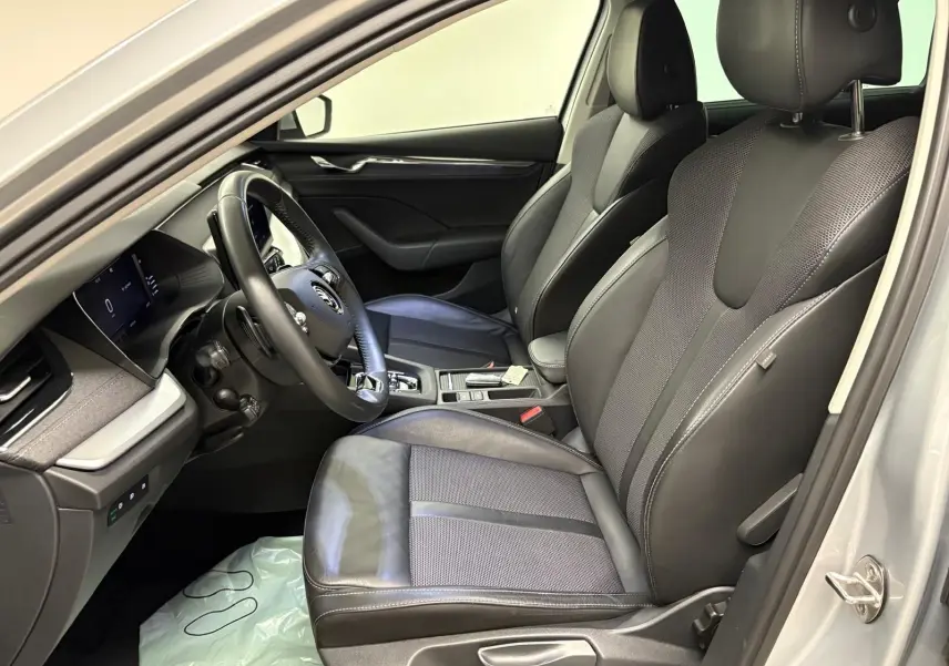 Intérieur côté conducteur de la Skoda Octavia Combi gris argent 2023, sièges cuir et tableau de bord moderne visibles.