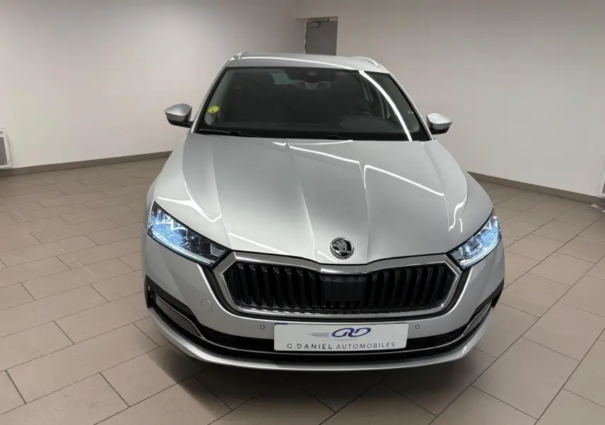 Vue avant d'une Skoda Octavia Combi gris argent 2023 avec phares LED allumés et calandre noire brillante.