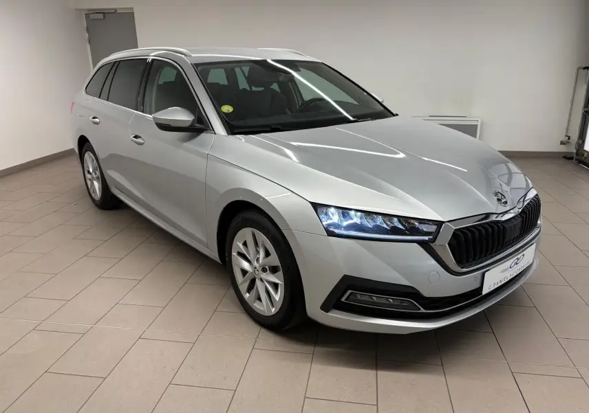 Skoda Octavia Combi gris argent vue 3/4 avant droit, phares LED allumés et calandre noire distinctive.