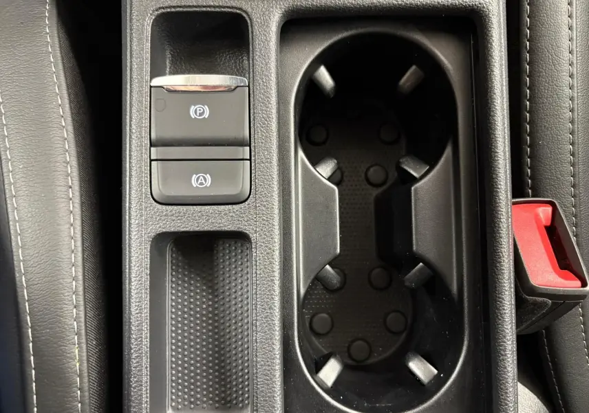 Gros plan sur la console centrale de la Skoda Octavia Combi gris argent, montrant les porte-gobelets et commandes électroniques.