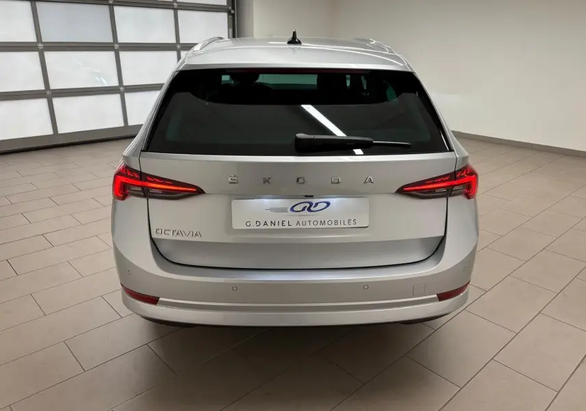 Vue arrière d'un Skoda Octavia Combi gris argent 2023 avec feux LED allumés dans un showroom.