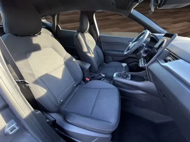 Intérieur avant du Renault Captur 2024, sièges tissu noir et tableau de bord avec boîte manuelle visible côté droit.