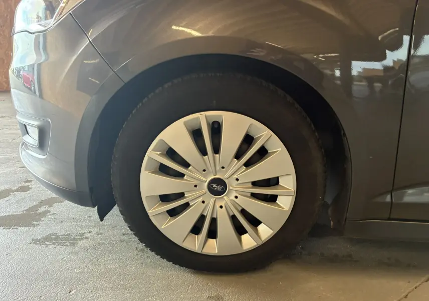 Gros plan sur la roue avant gauche d'une Ford C-MAX gris métallisé avec enjoliveur à rayons fins.