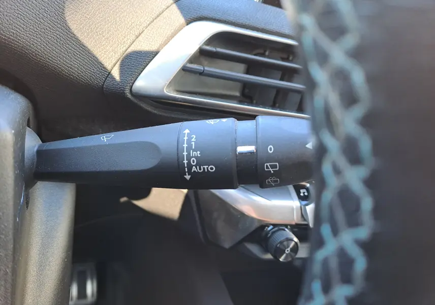 Gros plan sur la commande d’essuie-glace à gauche du volant dans l’habitacle gris d’un Peugeot 5008 2019.