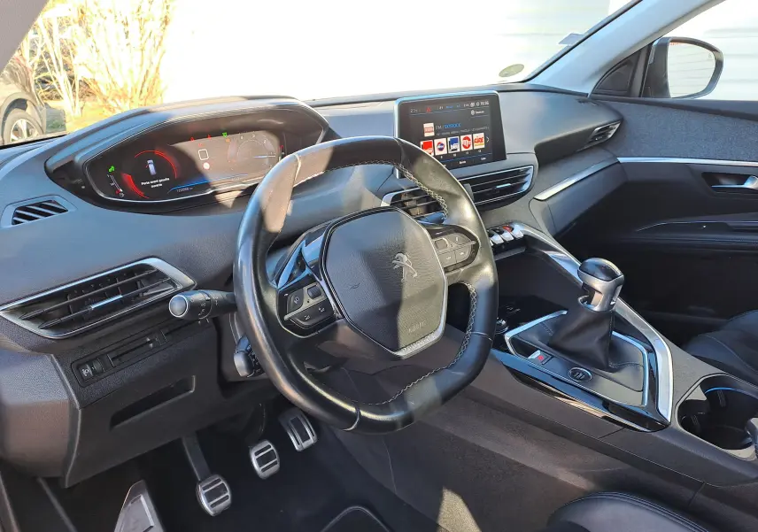 Vue intérieure côté conducteur du Peugeot 5008 2019, volant compact, tableau de bord numérique et levier de vitesse manuel.
