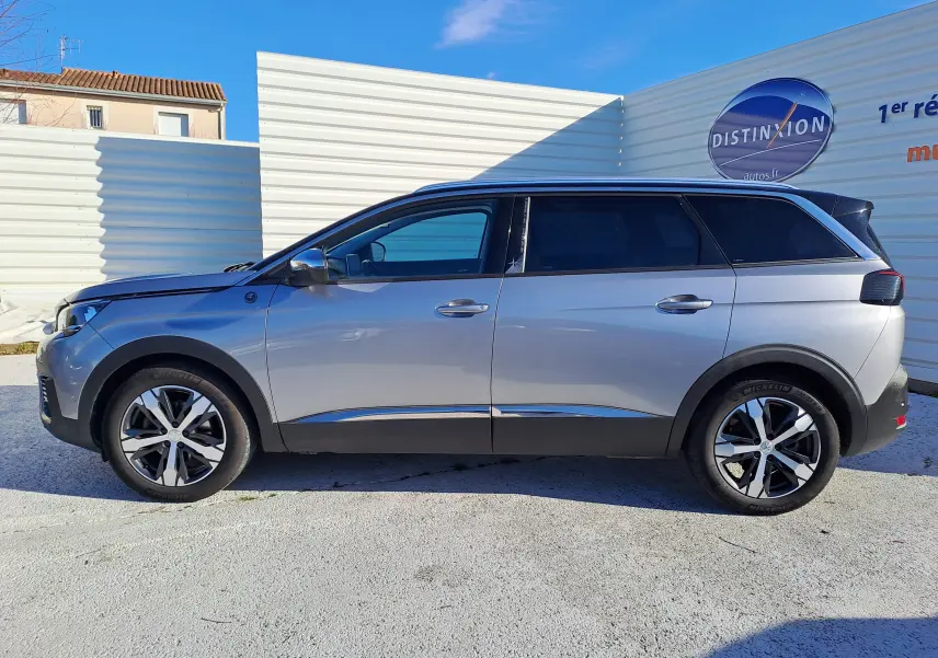 Profil côté gauche d'un Peugeot 5008 gris 2019, version Crossway 7 places, avec jantes alliage bicolores et vitres teintées.
