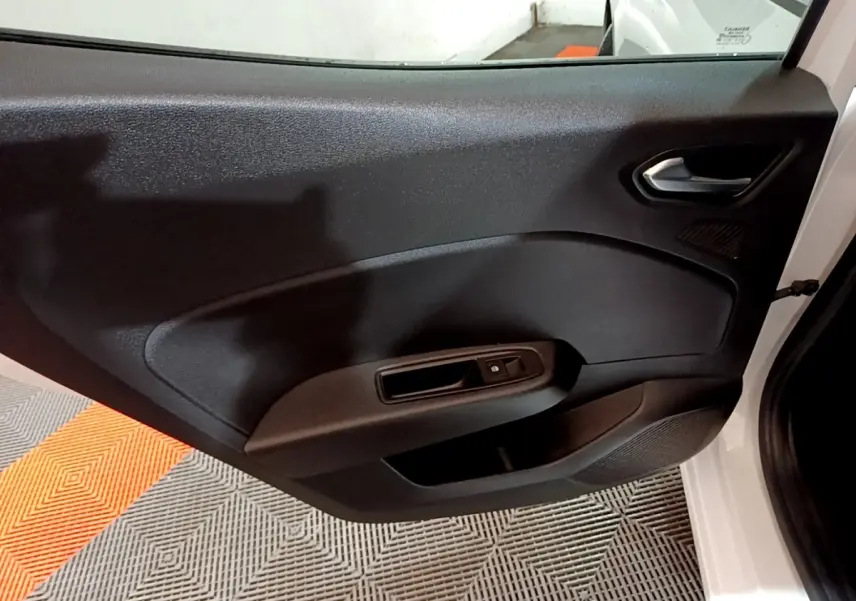 Vue intérieure de la porte avant droite noire d'une Renault Clio blanche 2023, avec poignée et commande de vitre électrique.