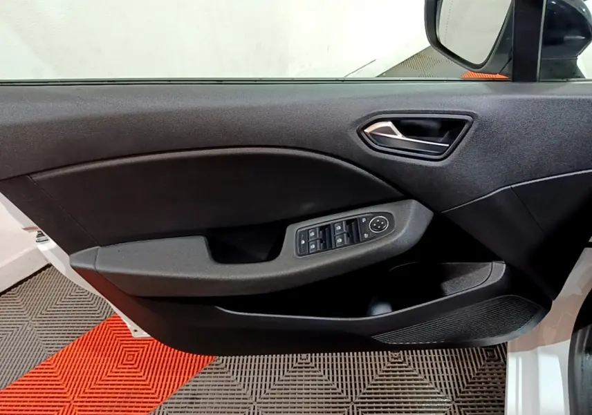 Vue intérieure sur la porte avant gauche noire de la Renault Clio blanche, avec commandes des vitres et rétroviseur visible.