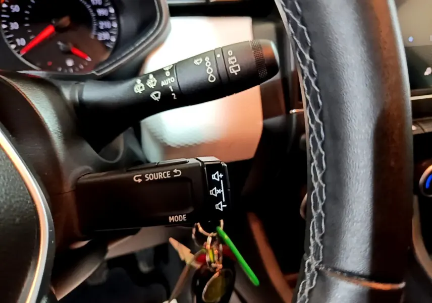 Gros plan intérieur sur la commande au volant et le commodo d’essuie-glace d’une Renault Clio Business blanche de 2023.