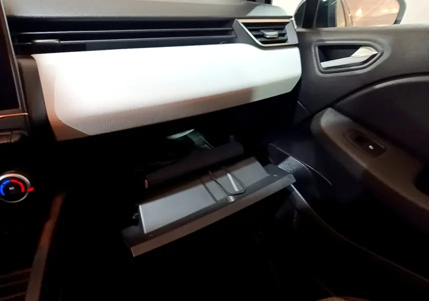 Intérieur côté passager de la Renault Clio Business blanc, avec boîte à gants ouverte et tableau de bord clair.