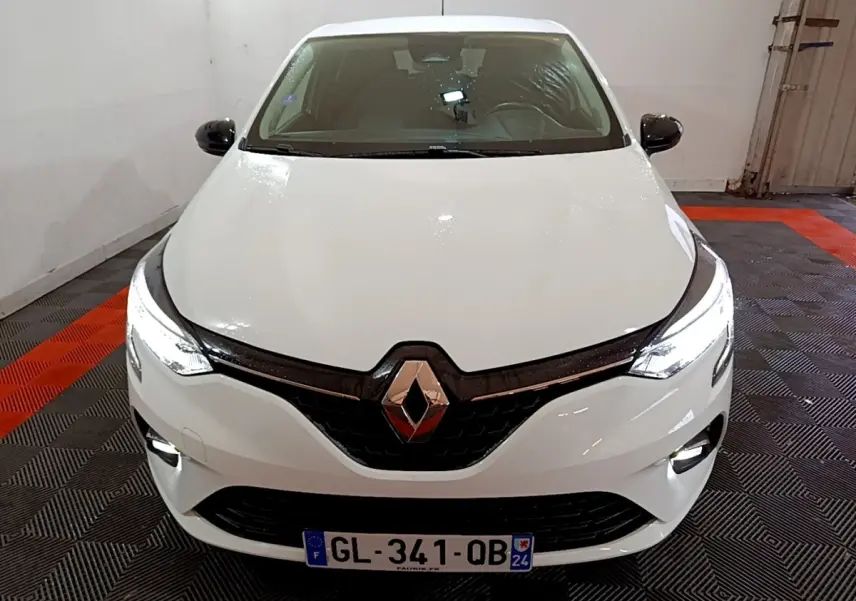 Vue avant d'une Renault Clio Business blanche avec phares LED allumés dans un garage.